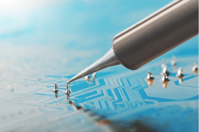 a close up of the tip of a soldering iron working on an electronic circuit board, a skill that is important when becoming IPC certified