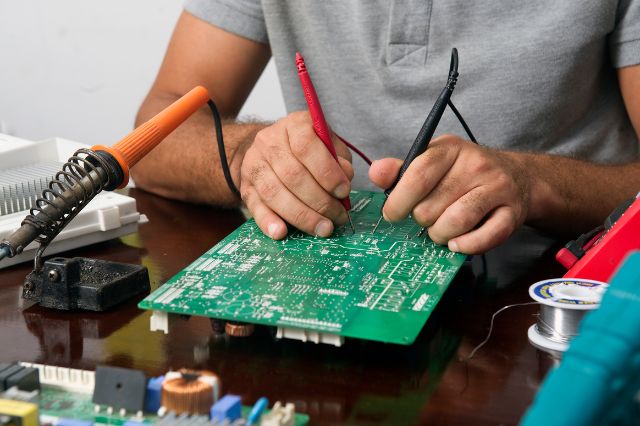 a man using electronics probs on a circuit board