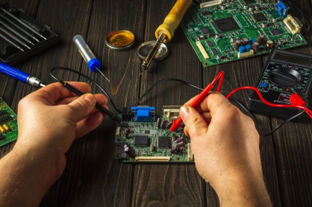 a pair of hands working on an electronic circuit board