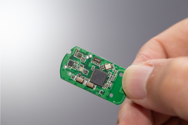 fingers holding up a tiny electronics chip with lots of micro components