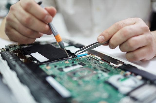 hands using a soldering iron on an electronics circuit board