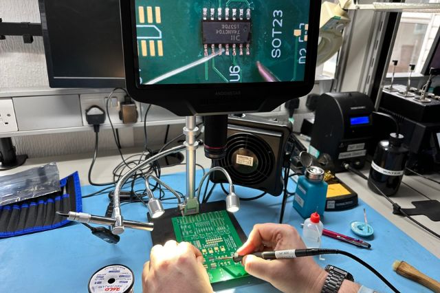 a delegate working on a pcb under a microscope using the screen to see their soldering work up close