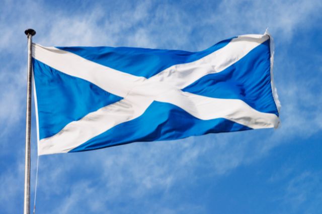 A Scottish flag flying in front of a blue sky