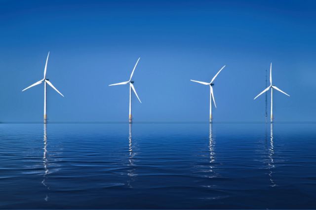4 windmills standing out to sea with clear blue skies