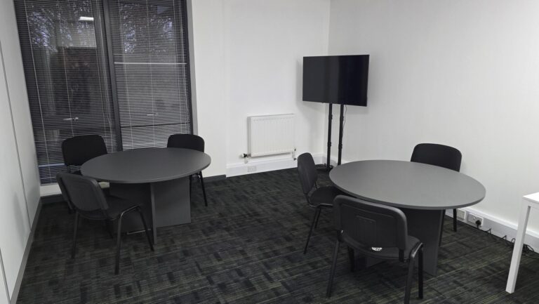 a clean new break room at our aberdeen training centre with 2 round tables with chairs and a tv screen