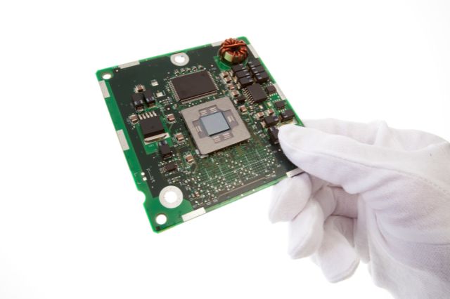 a gloved hand holding a PCB to spect if it has ionic contamination