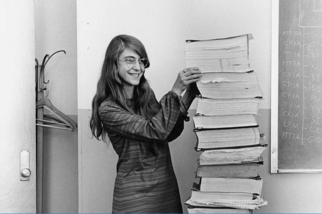 margaret hamilton holding a stack of papers from the work she did for nasa